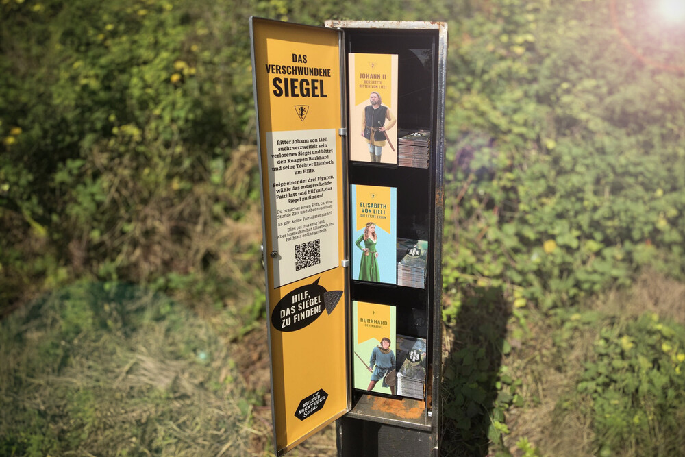 Faltblatt Dispenser, je Figur ein Faltblatt mit Rätsel – Kulturabenteuer «Burg Nünegg»